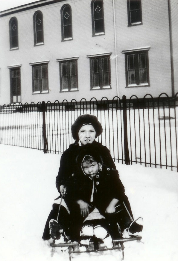 Delphine Atger on sled, with St. Joseph's Catholic Church in background