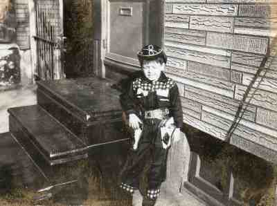 Child seated by the front steps, about 1961