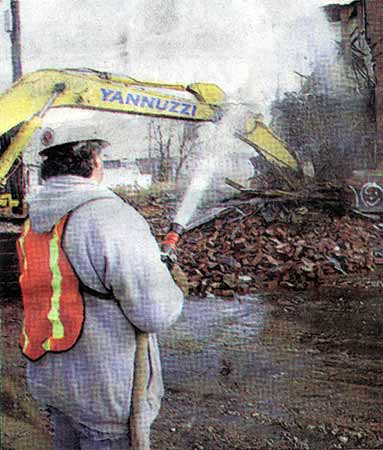 Max Leuzzi suppresses dust as a house is demolished on Arlington Street, February 5, 2004