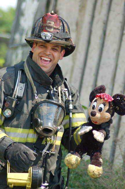 Fire fighter Matos of Ladder Company 3 holding a happy Minnie Mouse after reviving her from the blaze at 528 Borton Street, June 1, 2008