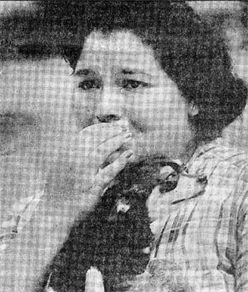 Carmen Alicea holds her dog Queeny as she watches the fire from across the street