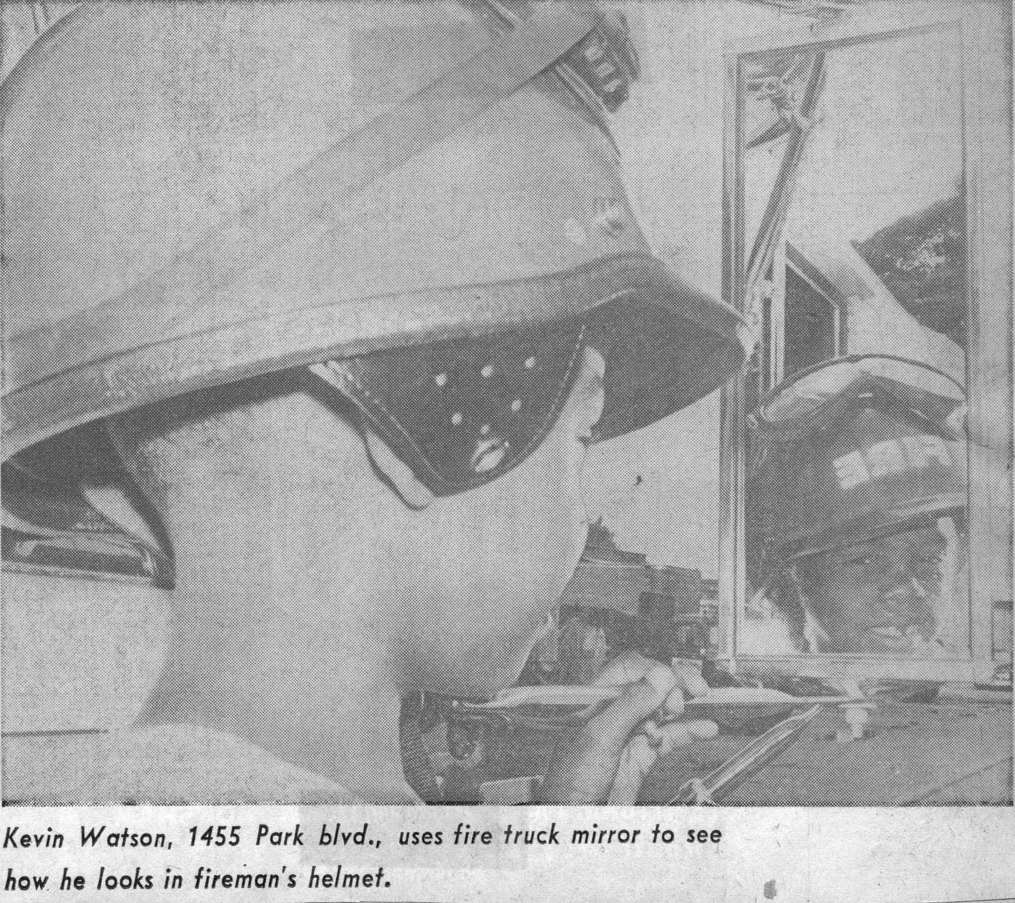 Kevin Watson of 1455 Park Boulevard uses fire truck mirror to try on fireman helmet, August 13, 1968