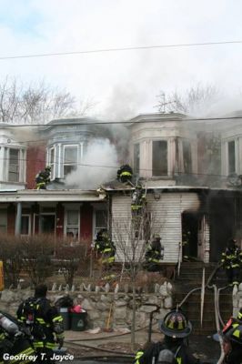 Fire fighters on porch roof of 931 and 933 Vine Street