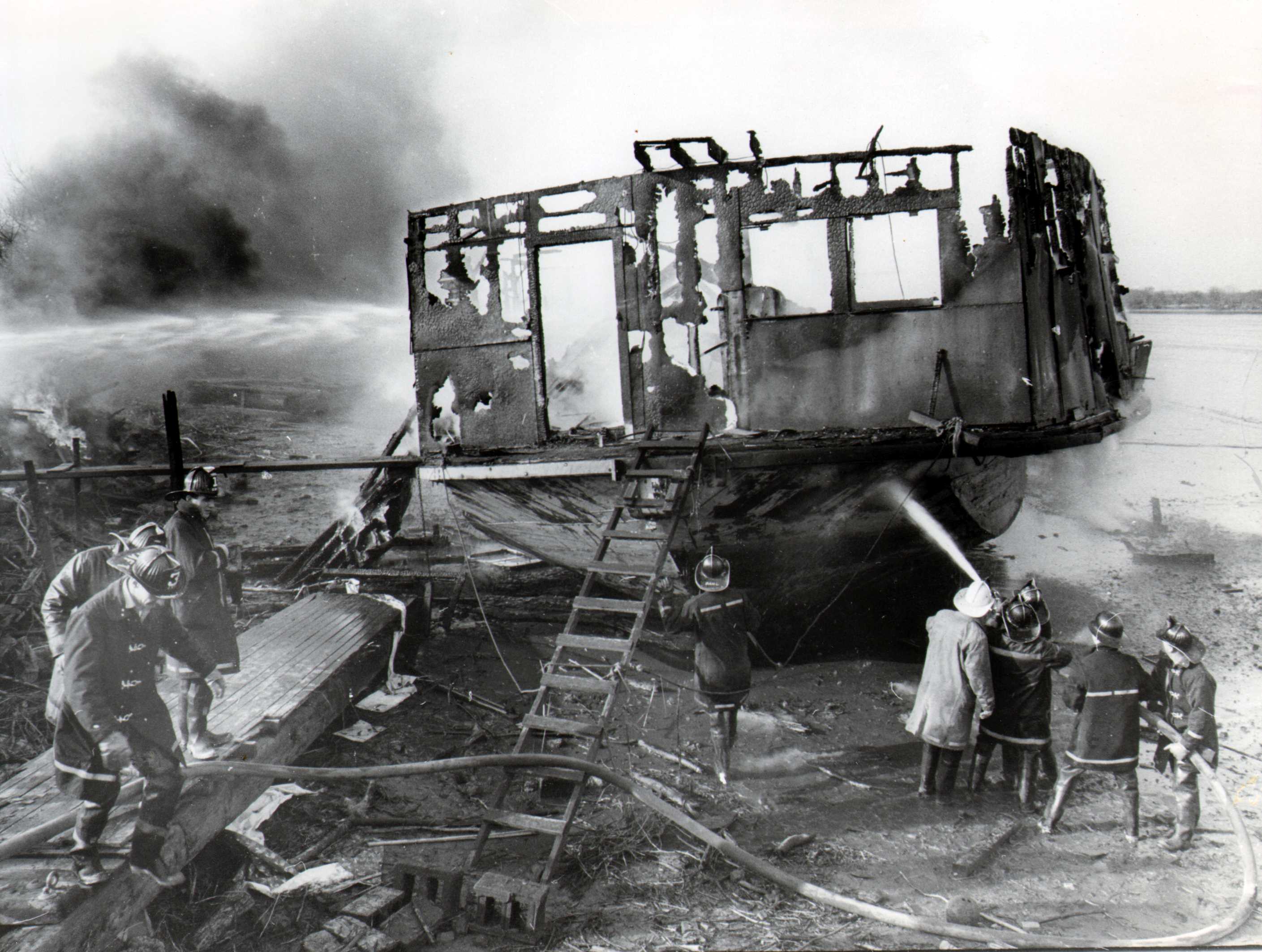 Derelict scow at low tide on the Cramer Hill mud flats, Engine 11 fighting the fire, February 17, 1965