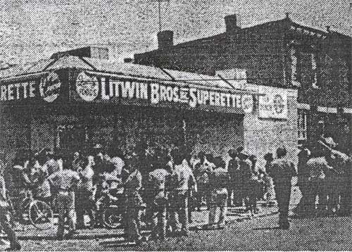 Neighbors crowd outside the Litwin Brothers Superette at Elm Street, Camden, after six persons were shot during an armed holdup attempt