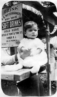 Carl W. Weber in front of a sign advertising the bottled soft drinks of North Camden businessman Oscar B. Weidenhammer, located at Point and York Streets. July 4, 1923.