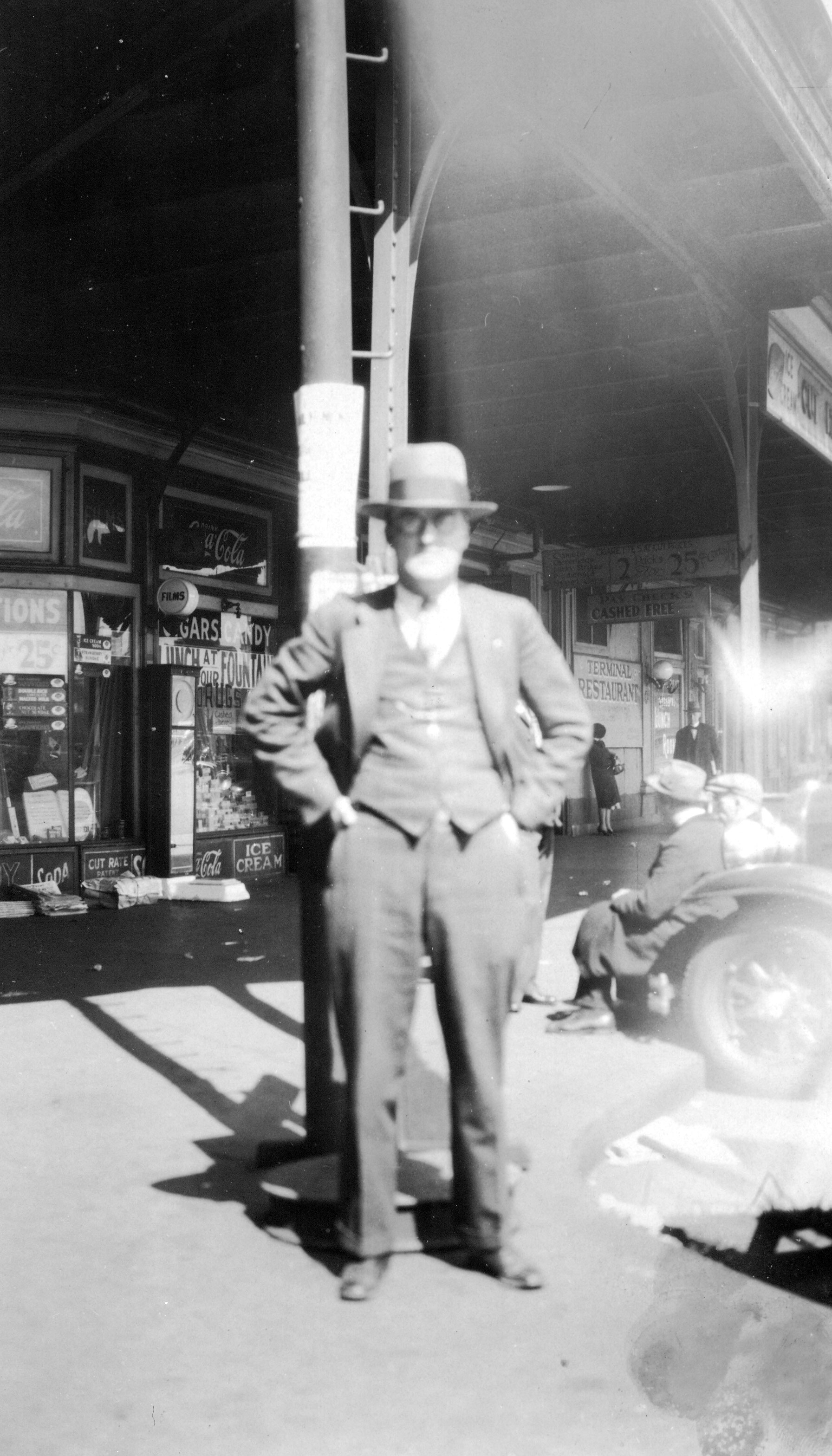 Unidentified man in front of shops at the Ferry Terminal, August 1929