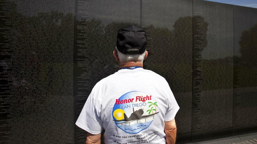 George Newton watches as a Vietnam Memorial docent creates a pencil rubbing of his son Barrie's name