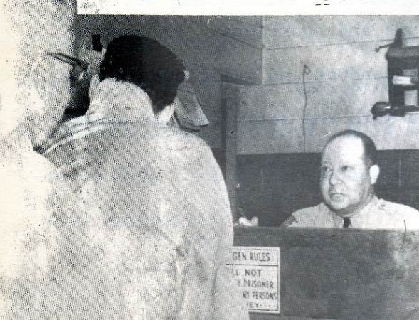 Suspect At Booking Desk — Dominic Palese seated behind desk