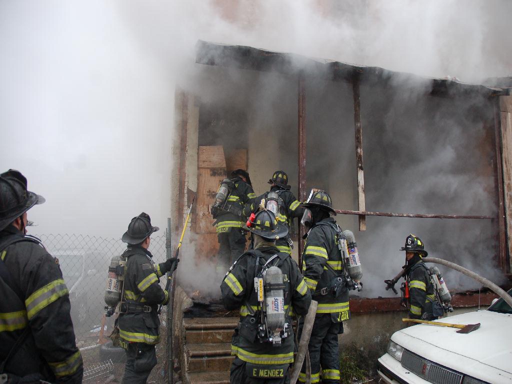 Fire fighter uses a chainsaw to cut through a boarded-up door, Bailey Street, December 13, 2007