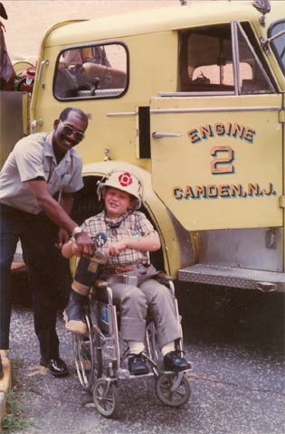 Ralph Roberts with the Muscular Dystrophy Association Poster Child with Engine Company 2's 1967 American LaFrance pumper, early 1980s