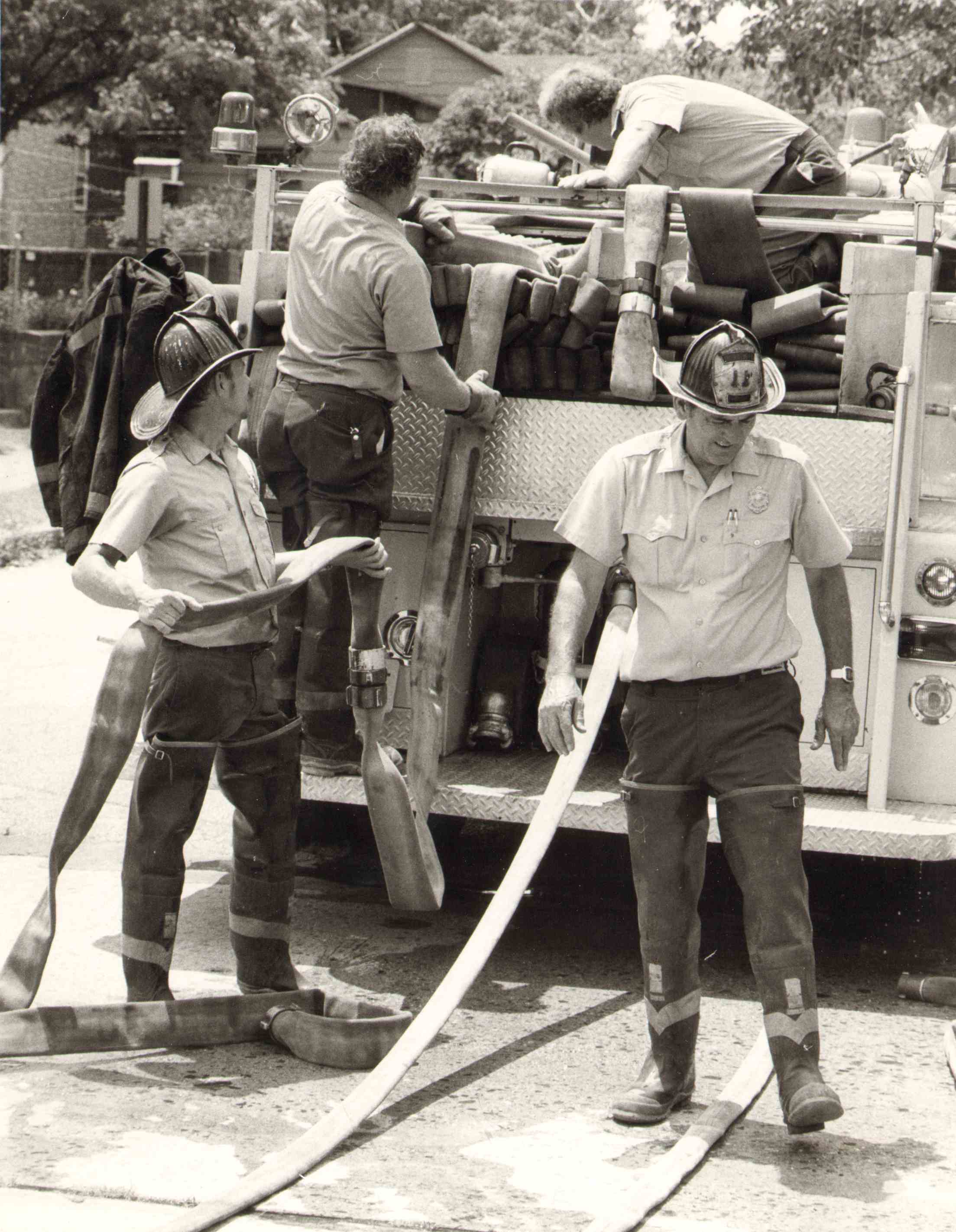 Captain Jim McGrory of Engine Company 11 and crew packing hose after a one alarm house fire at North 35th Street and Harrison Avenue, July 1, 1980