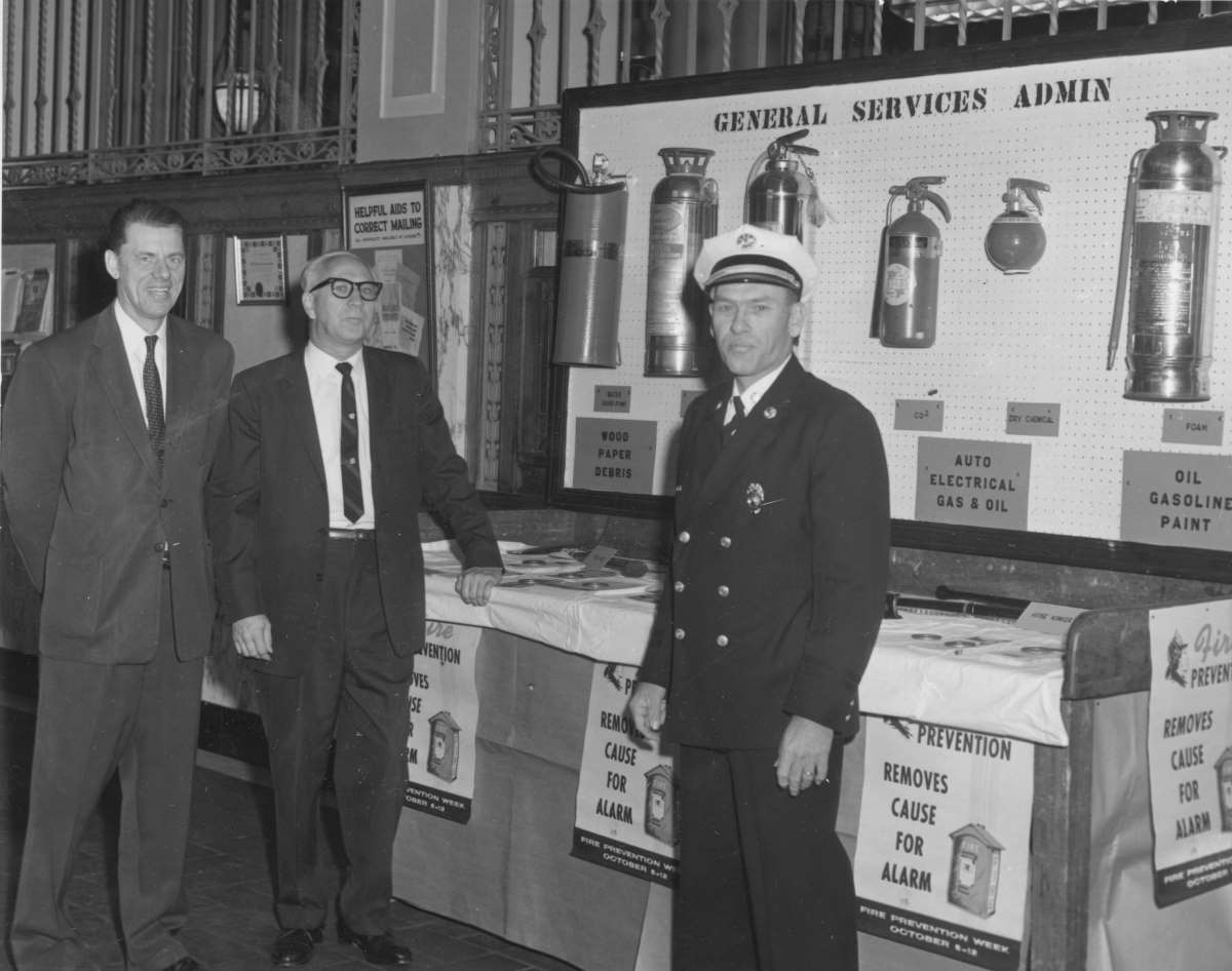 Lobby Display at the U.S. Post Office, 1963: Mr. Espaland, Building Manager; Mr. Wallace, Personnel Manager; Chief George Baxter, Fire Marshall