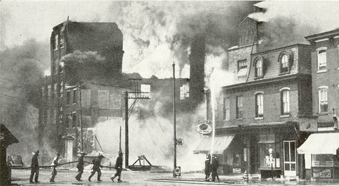 Firemen with hand lines are shown checking the spread of the fire to the east along Market Street, Camden