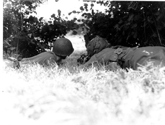 photo: sc 364299 - two g.i.'s of the 2d infantry division, operate a .30-caliber light machine gun from under cover of low-hanging trees.they are firing at a hedgerow across a clearing near vire, france.12 august 1944 (norbuth)