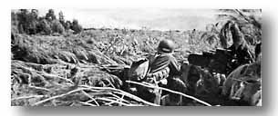 An infantry officer takes cover in an abandoned enemy emplacement as German mortar fire sweeps the beaches