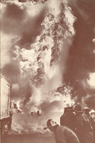 Camden NJ firemen advancing line as explosion rips 3-alarm fire at paint company, May 1967