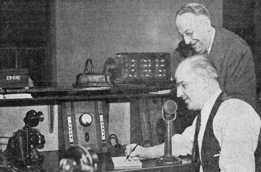 James A. Howell standing behind Chief Operator Ed Garrity who is seated at the two-way radio console in the Camden police dispatch room, 1933