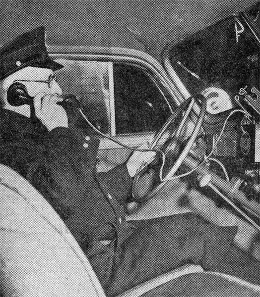 Patrolman William Michalak in a patrol car, testing the new two-way radio system with handset, 1933
