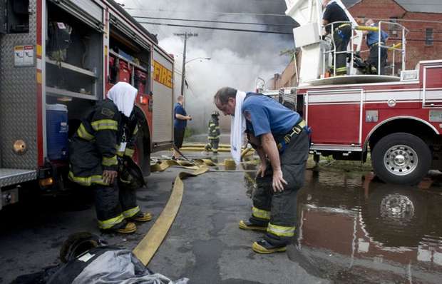 As temperatures near 100 degrees, firefighters catch their breath during the battle against a fire that began in a vacant Camden warehouse