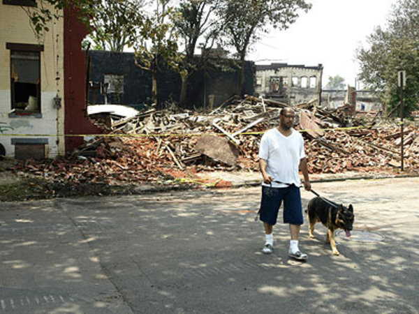 Dennis Missouri and his dog, Cash, walk away Friday from the fire-damaged rubble which was his home 16 years ago along Louis Street in Camden