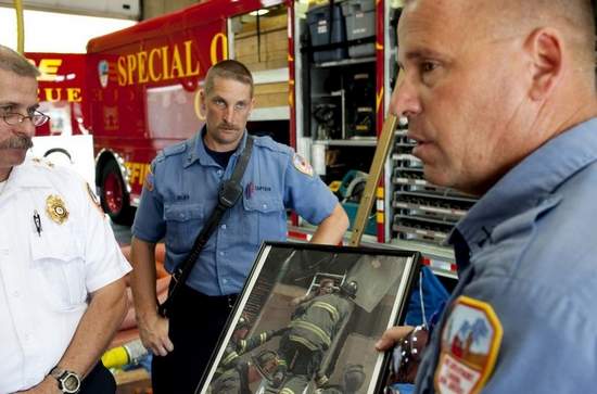 Capt. Frank Sandrock shows a photograph of a fire rescue as acting Chief David Yates and Capt. David Dilks look on