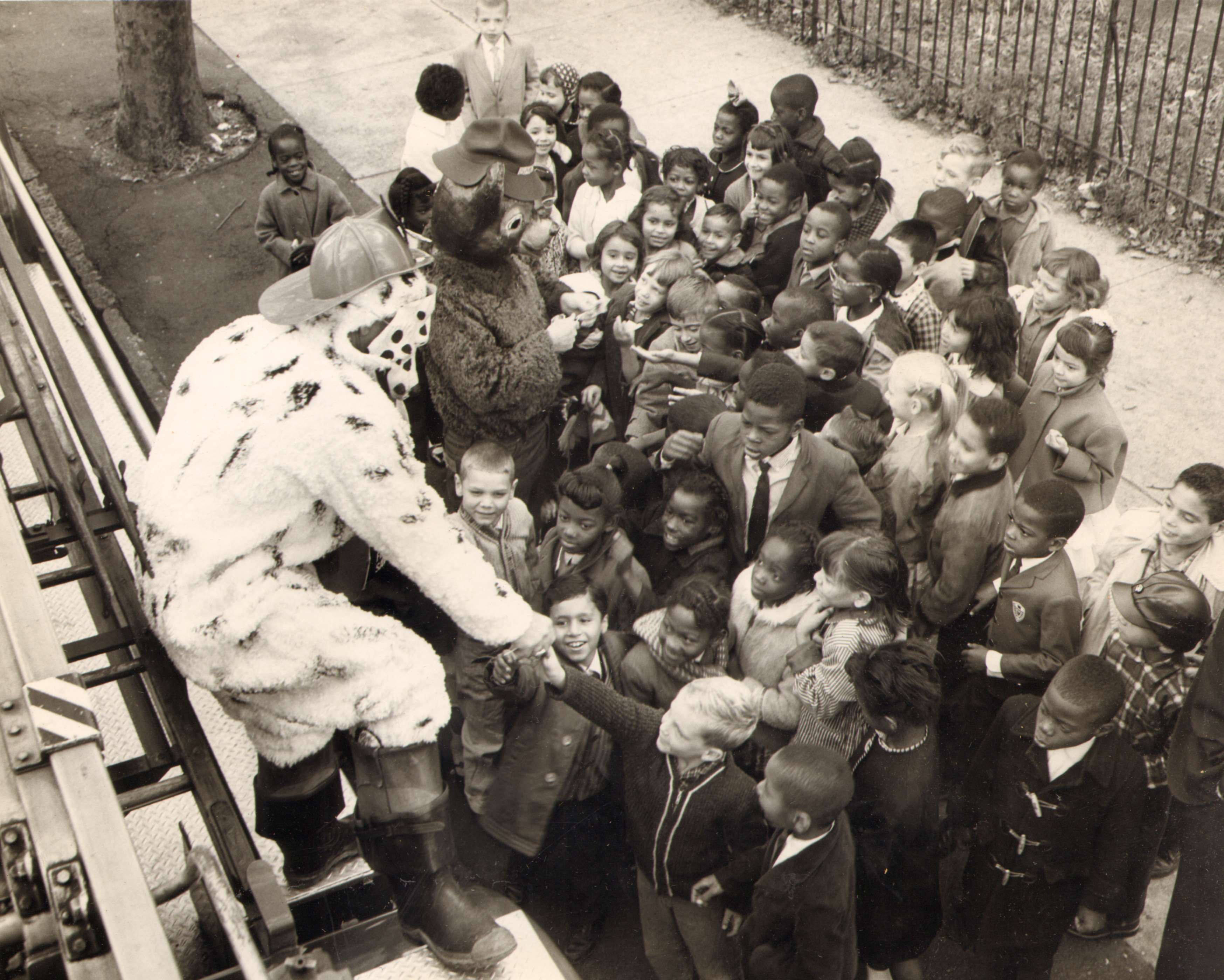 "SPARKY" and "SMOKEY" giving candy to school children — Chief George Baxter as Sparky, Inspector Kenneth Clark as Smokey