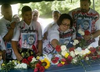 Myrna Rubert and Jose Rosa, mother and father of 9-year-old Jacob Rosa, place flowers on his coffin during Rosa's funeral at Arlington Cemetery in Pennsauken