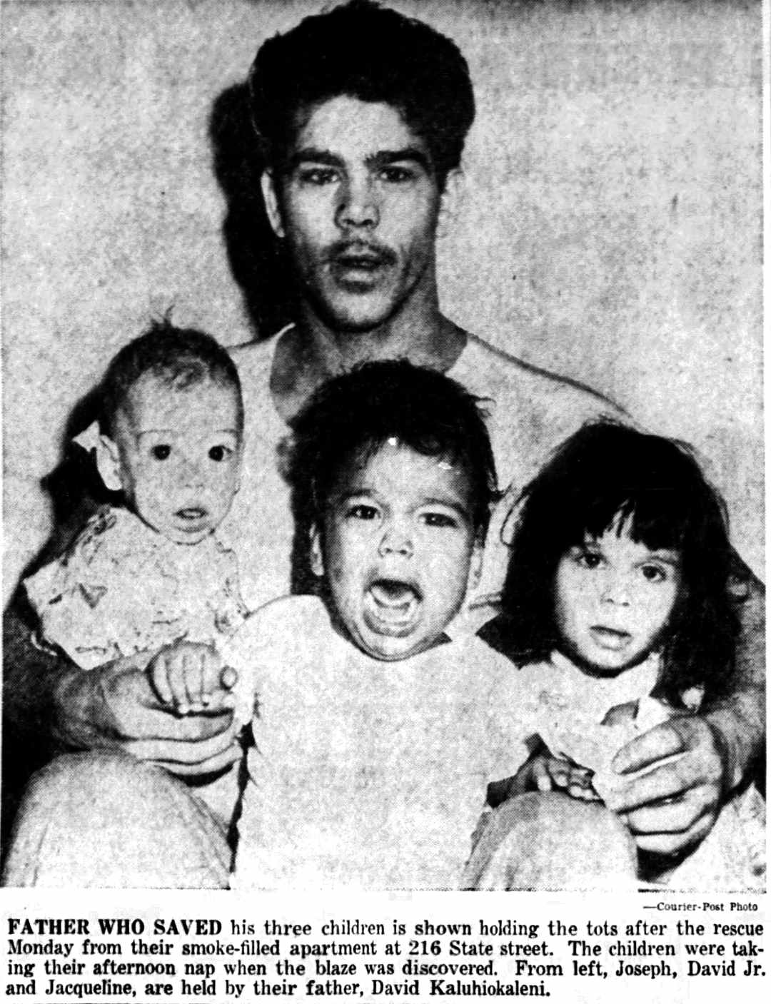Father David Kaluhiokalani holds his three children after the rescue from their smoke-filled apartment
