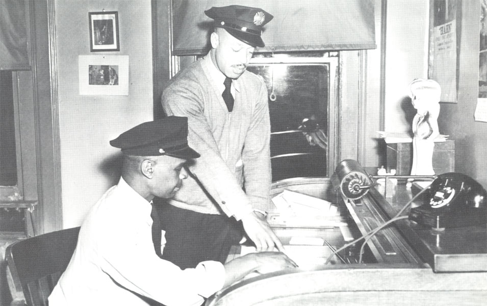April 1948 — In the company office of Engine Company 1, South 4th and Pine Streets. Seated: Captain Raymond Amos; standing: Captain Jesse Jones.