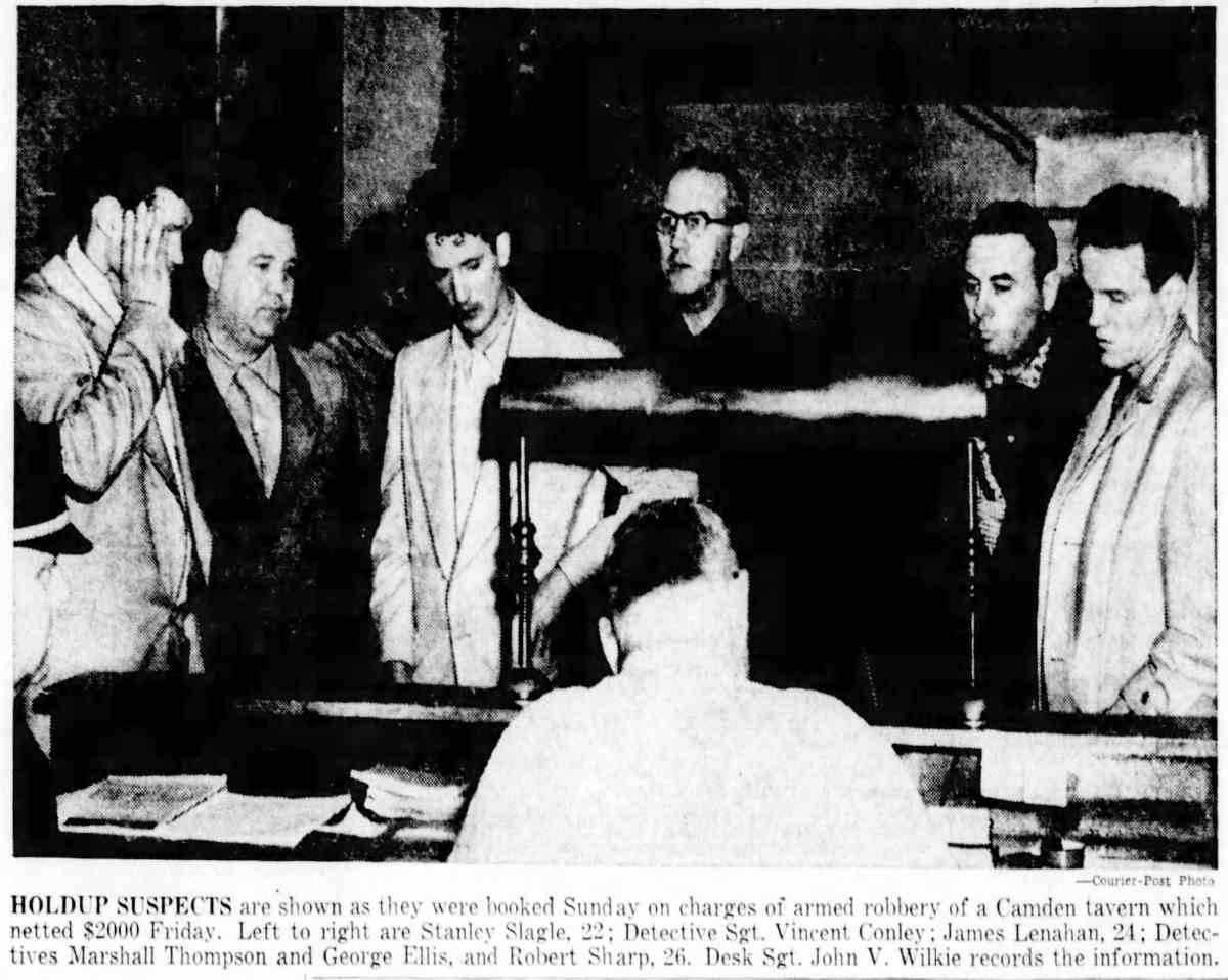 Holdup suspects booked — Stanley Slagle, Detective Sgt. Vincent Conley, James Lenahan, Detectives Marshall Thompson and George Ellis, Robert Sharp. Desk Sgt. John V. Wilkie records the information.