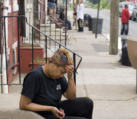 Juanita Wiggins, 43, sits outside her Sycamore Street home in Camden. Her husband Kevin Wiggins, 49, was murdered early Thursday morning on the corner of the block.