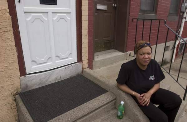 Juanita Wiggins, 43, sits outside her Sycamore Street home in Camden. Her husband Kevin Wiggins, 49, was murdered early Thursday morning on the corner of the block.