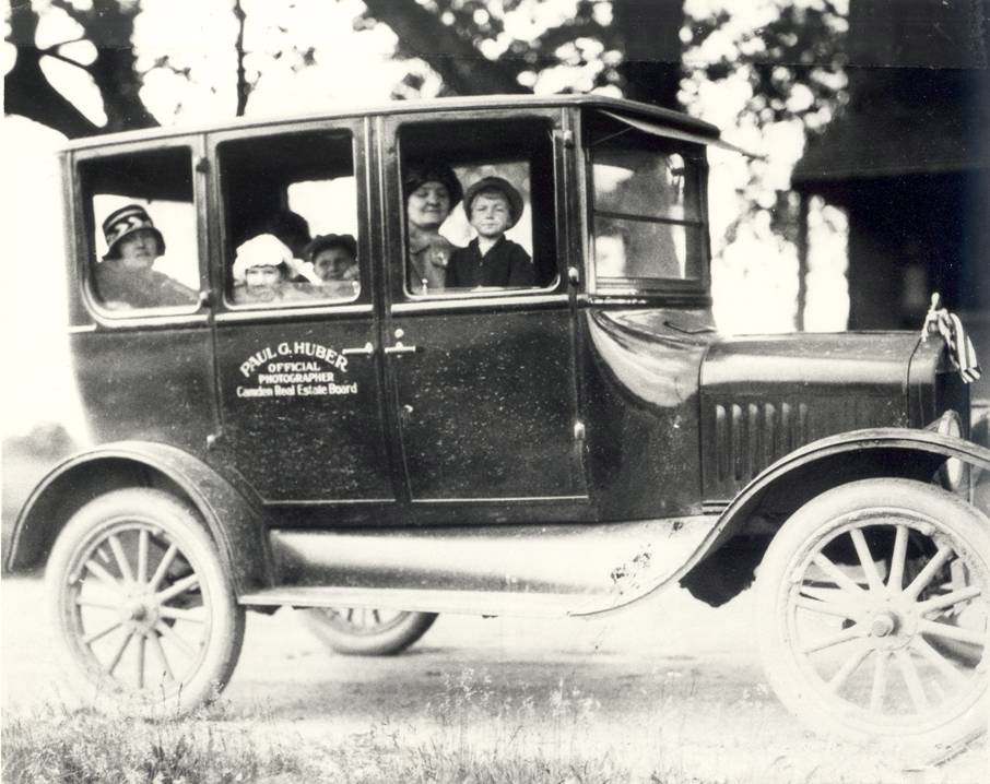 Paul G. Huber's family posing with car labeled Official Photographer Camden Real Estate Board