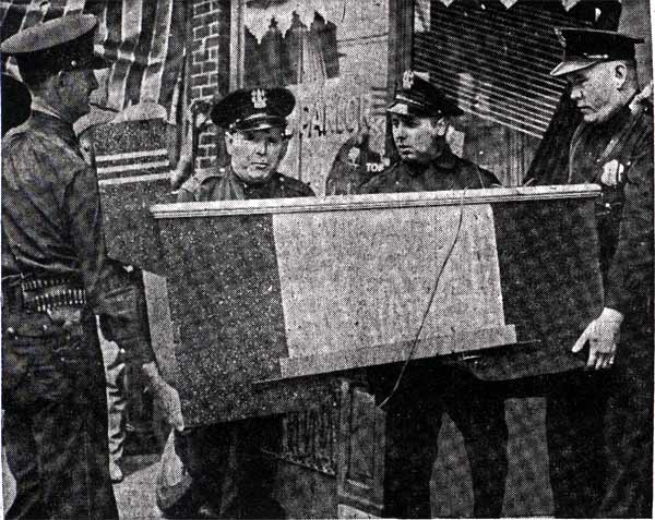 Camden police carrying the seized pin-ball machine from 1808 Broadway