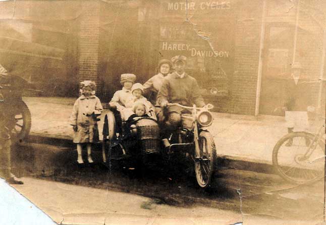 William Heckenhorn astride a Harley-Davidson motorcycle, with his wife Mabel in the sidecar holding son Howard, early 1910s