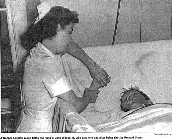 A Cooper Hospital nurse holds the hand of John Wilson, 9, who died one day after being shot by Howard Unruh. Camden Courier-Post - September 7, 1974