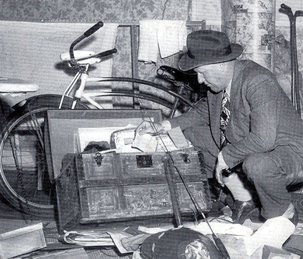 Camden County Detective James McLaughlin checks out items belonging to Howard Unruh in the Unruh home on River Avenue, Camden in 1949. McLaughlin had been investigating Unruh's killing spree in 1949. Camden Courier-Post. September 7, 1949