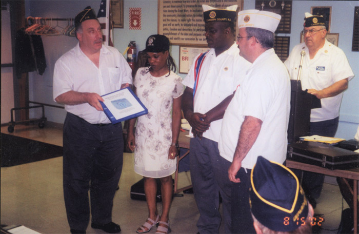 Phil Cohen and Debbie Williams presenting a book about the Rohna Memorial Ceremony to Camden County Commander Victor Lofland, 2002